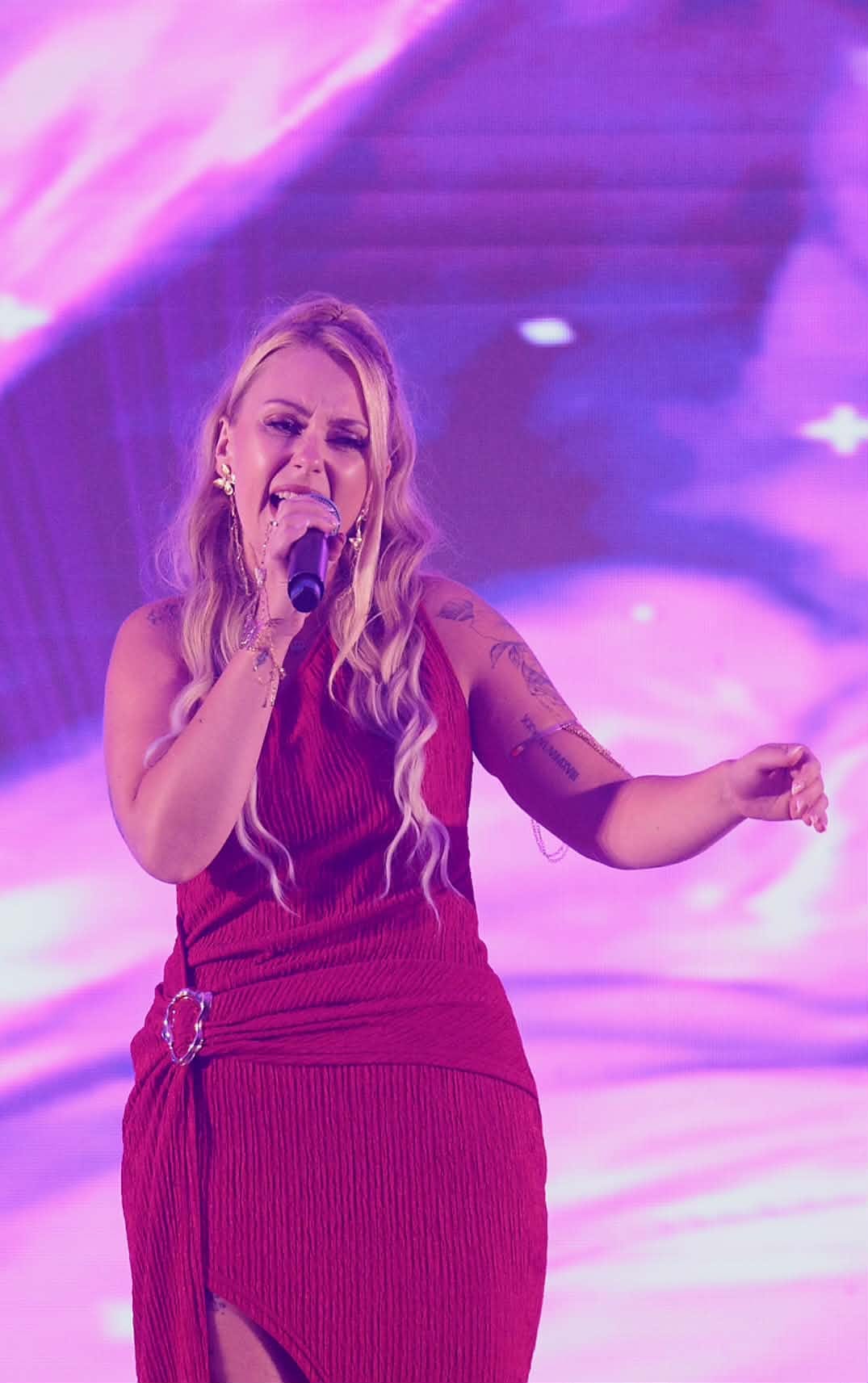 Justyna Misiak w bordowej sukni śpiewająca na scenie